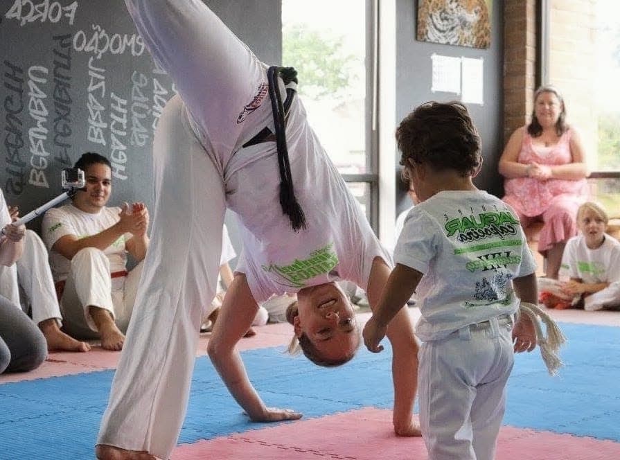 A young student training capoeira with a parent watching at Equipe Jaguar Capoeira